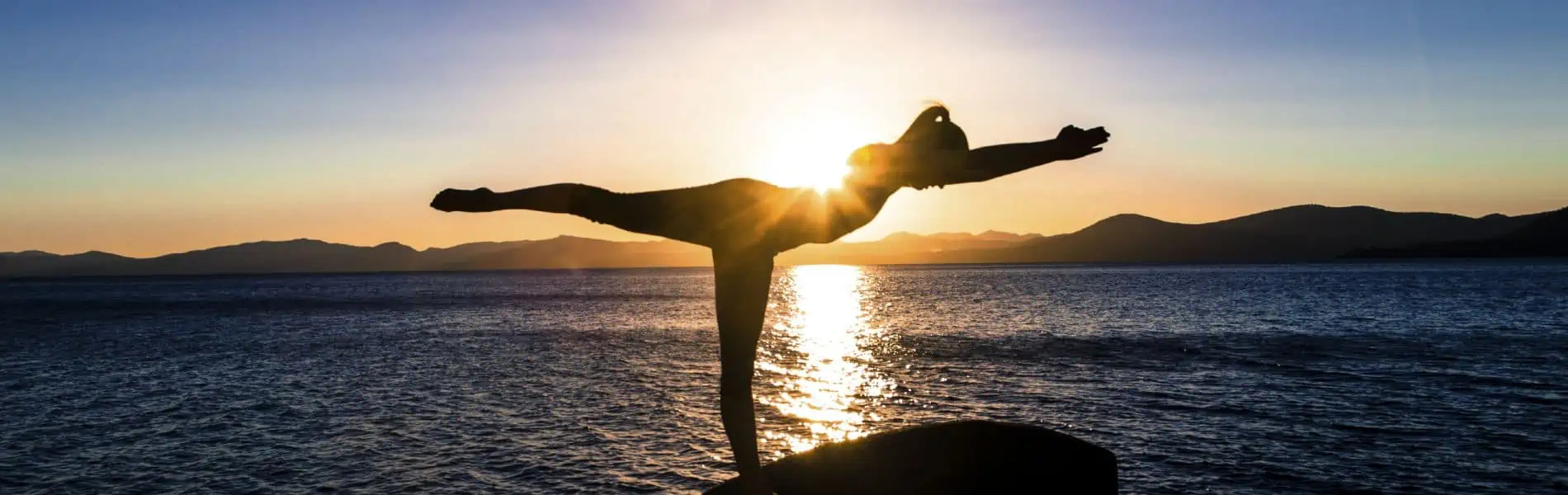 Woman doing yoga pose by the ocean.